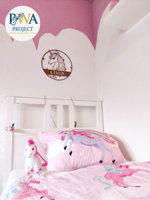 Metal wall art sign of a unicorn with a personalized name on it while it is hanging on the bedroom wall of a little girl