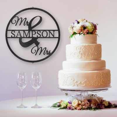 metal wall art sign as wedding decor behind a big wedding cake. The steel sign is personalized with the last name of the couple