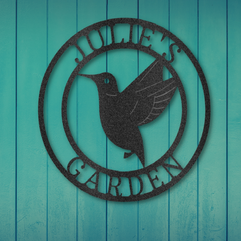 Metal Wall Art Sign of a hummingbird inside a ring that you can personalize with your own text or name. Hanging on the wall in het color black