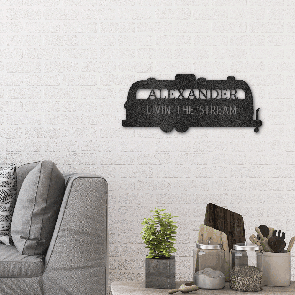 Silhouette of a airstream trailer as a metal wall art piece. Personalize this steel sign with any name or fun text. This metal decor is available in the color black. Hanging in a living room.