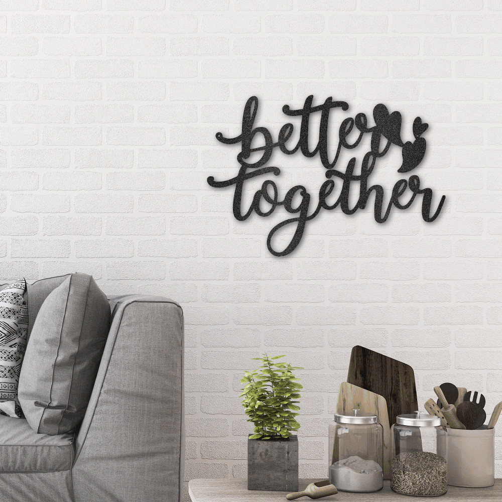Metal wall art sign that is the quote 'Better Together' with three little hearts. A perfect gift for a loved one. Hang this on your wall for years to come. This picture shows the design in the color black hanging in the living room above a couch