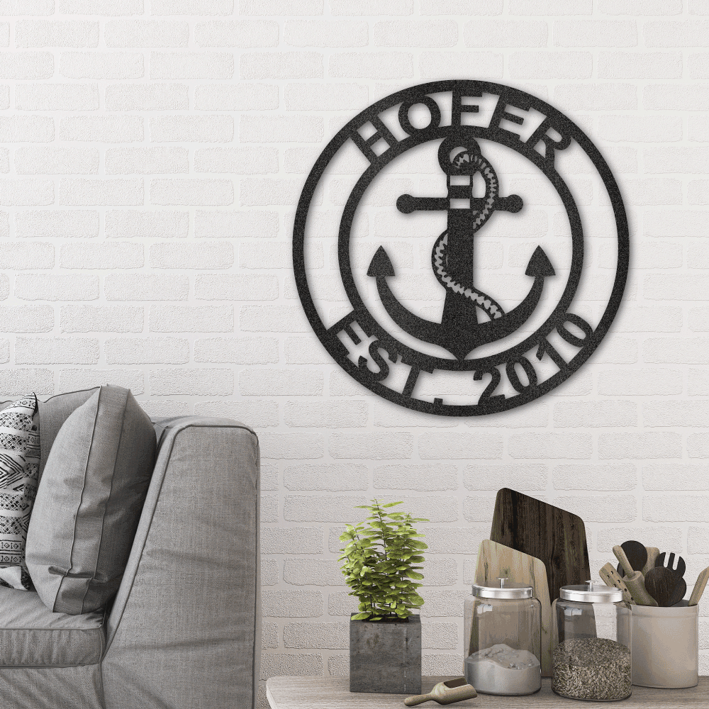 Metal wall art sign as a home decor of a circle with a nautical anchor that you can personalize with your own name, text or date. Hang this indoor or outdoor. Available in the color black. This picture shows the metal art hanging on the wall in the living room.