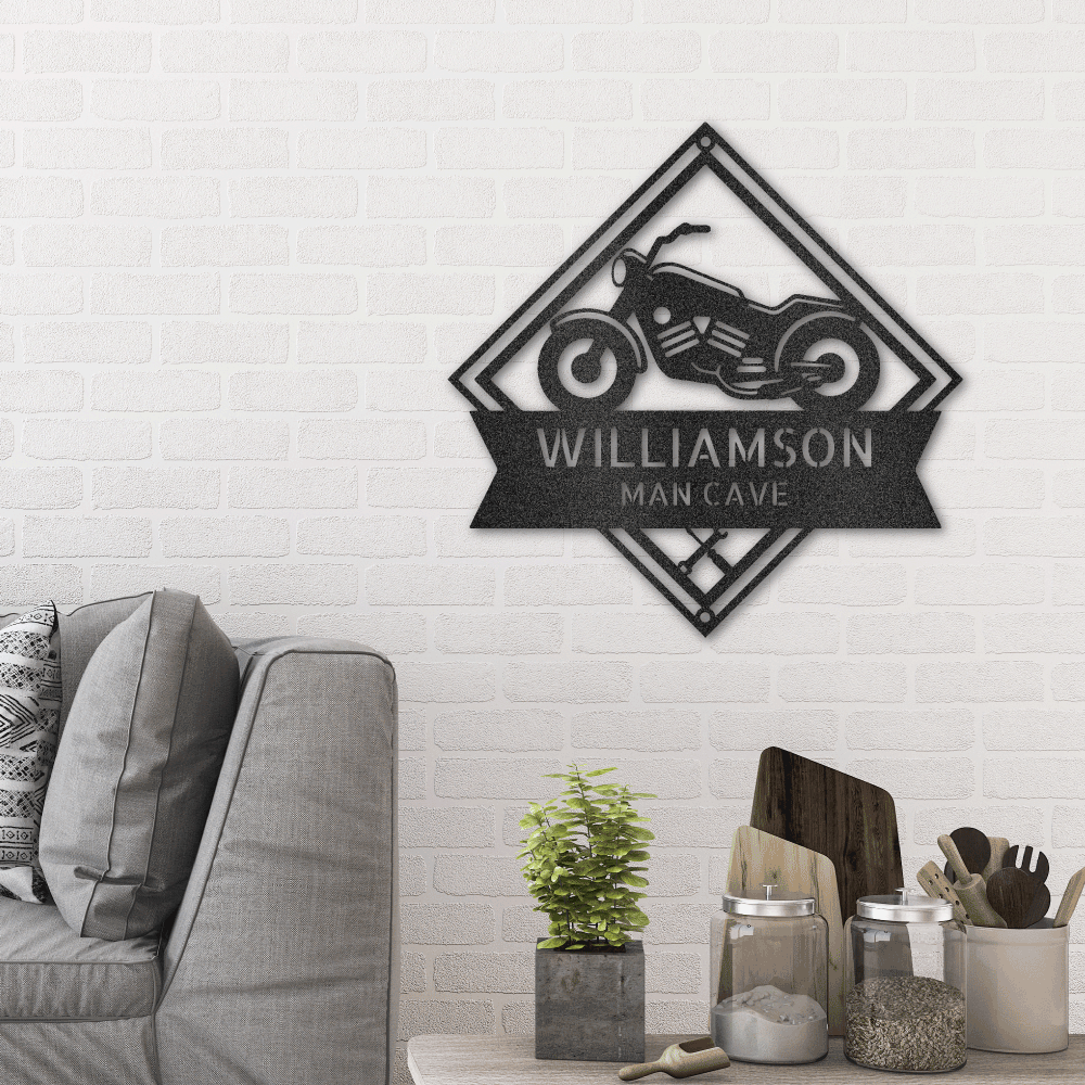 Metal wall art sign of a motorcycle with tools and a banner that you can personalize with your own name or text. This picture shows the design in the color black and is hanging on the wall of the living room above a couch